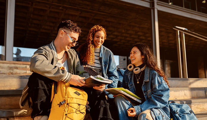 Estudiantes multiétnicos riendo y estudiando juntos en las escaleras del campus