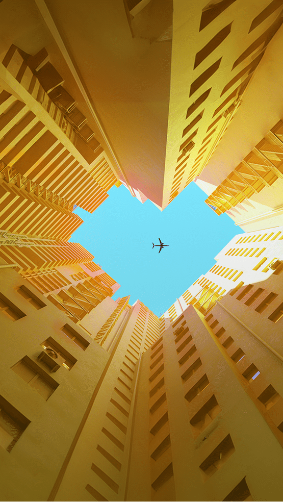 Digital generated image of orange buildings making heart shape with airplane flying on blue sky.