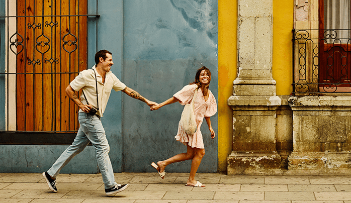 Wide shot tourist couple running through the streets of old Oaxaca