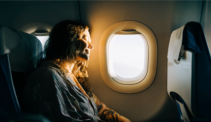 Serene female passenger enjoying sunny view from airplane window