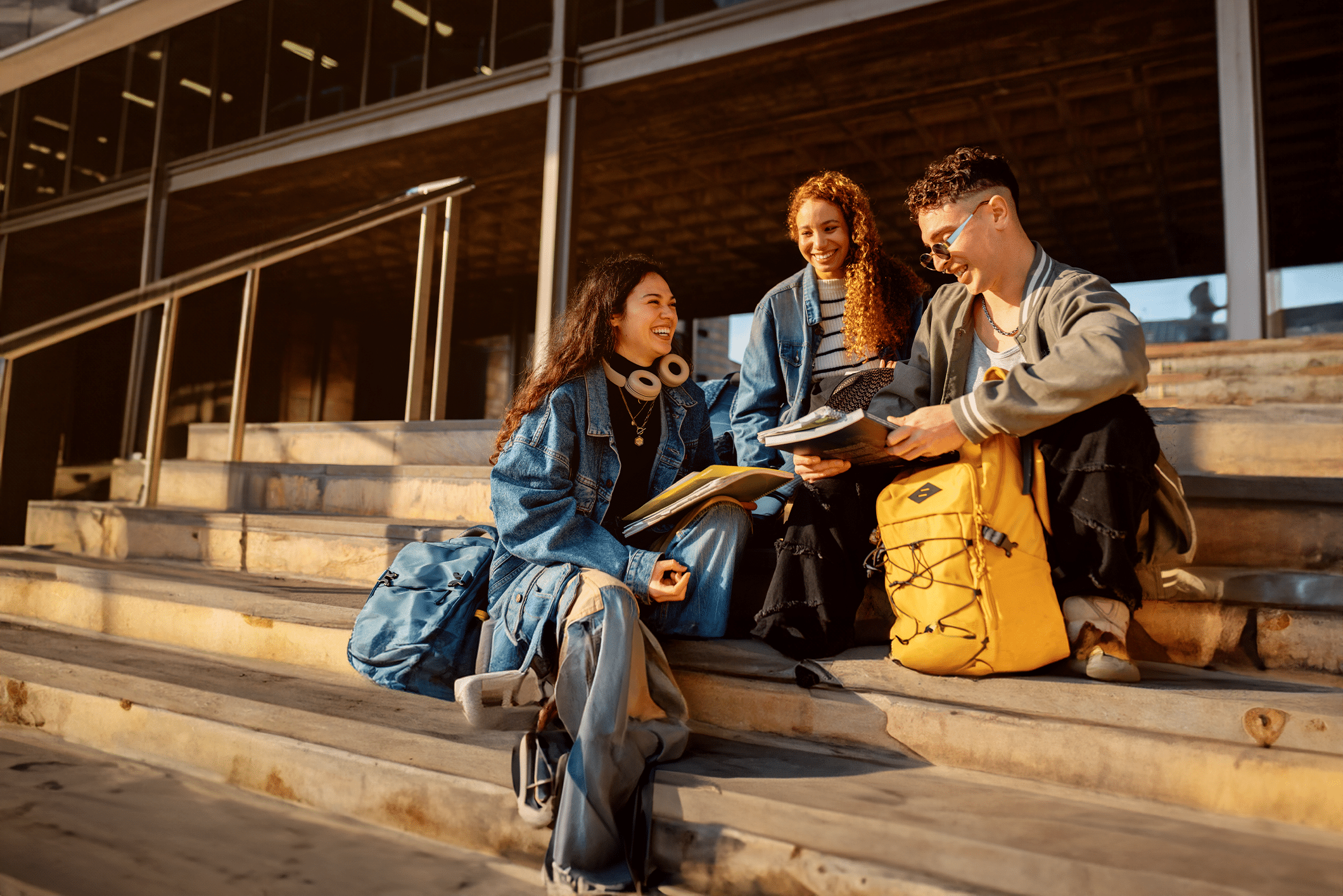 Estudiantes multiétnicos riendo y estudiando juntos en las escaleras del campus
