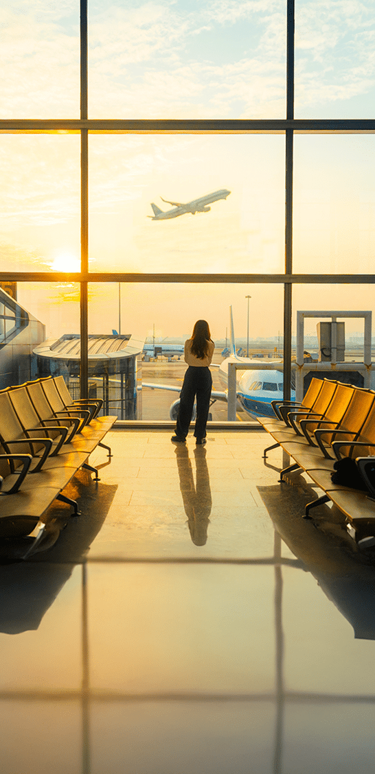 A young woman is using a smartphone to check the arrival departure board and flight schedule at the airport. - Fotografía de stock