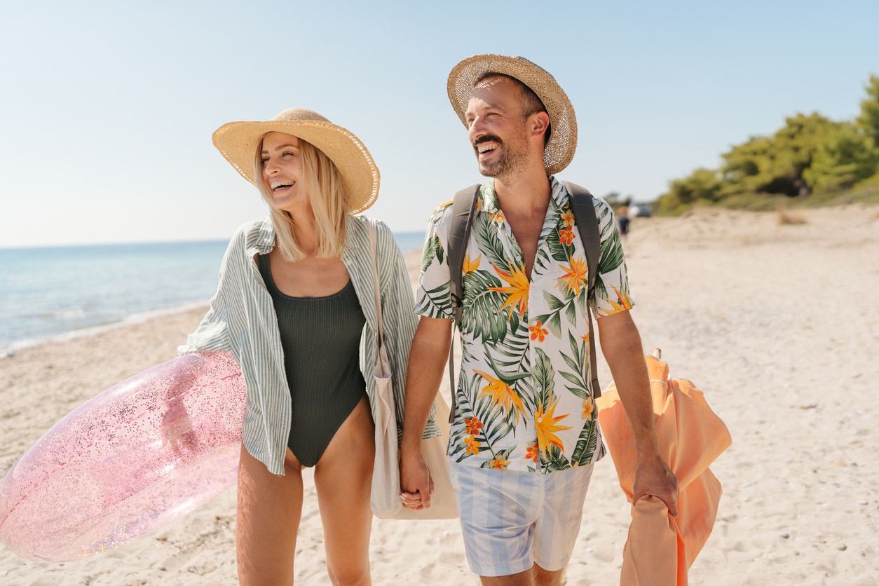 Smiling couple arriving at the beach viajar con calor agosto consejos racc