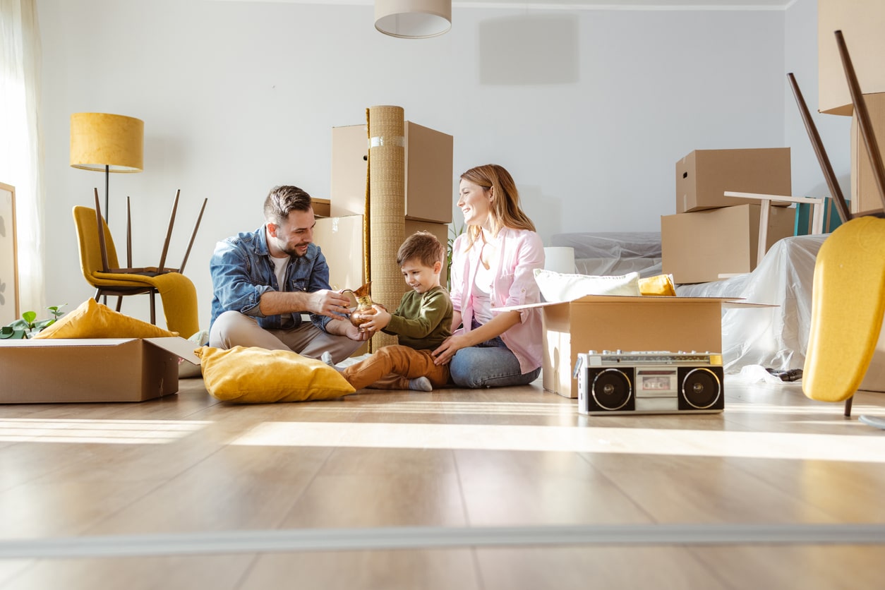 Happy young family unpacking belongings from boxes in new apartment consejos para una mudanza del hogar