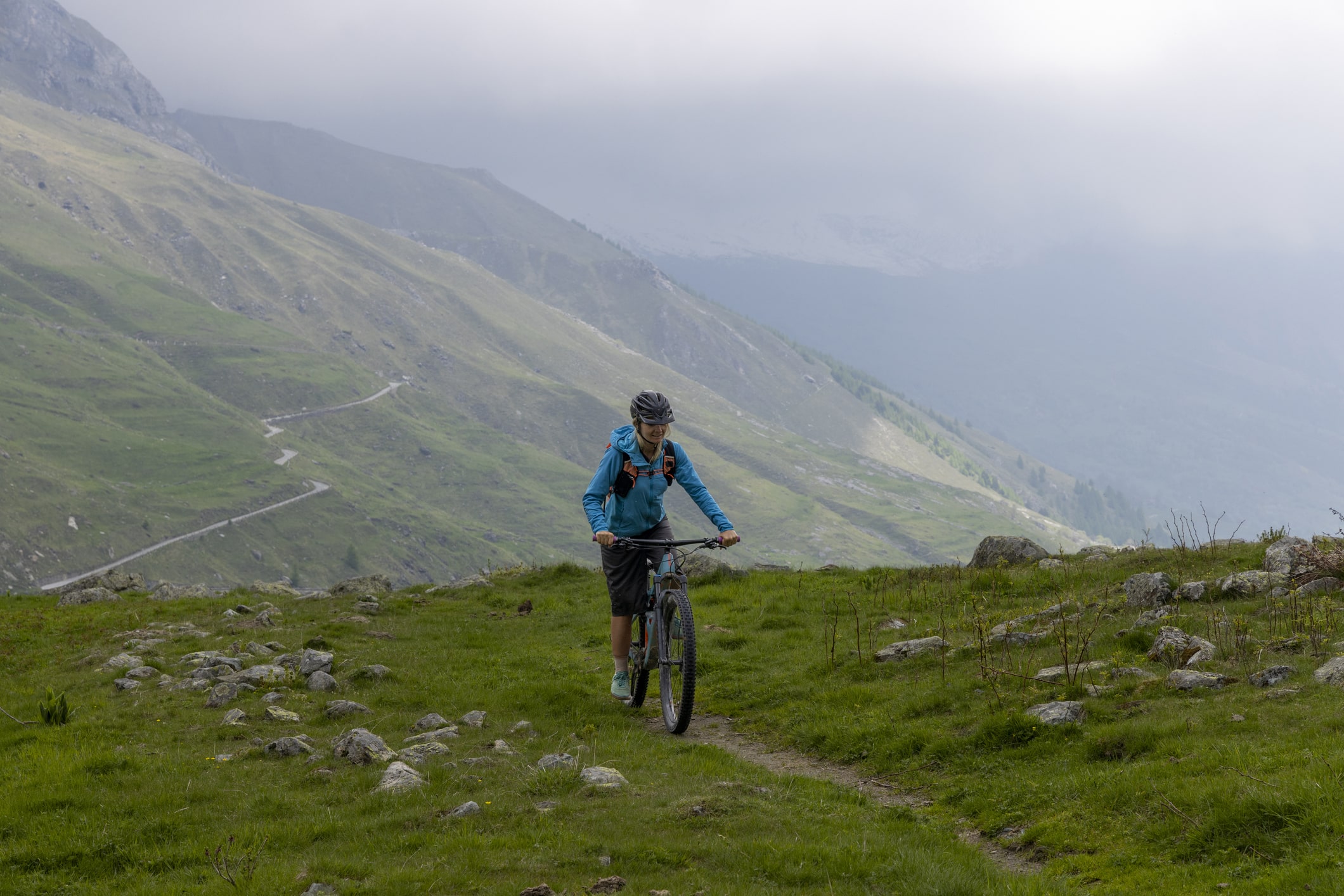 Young woman rides e-bicycle up mountain trail